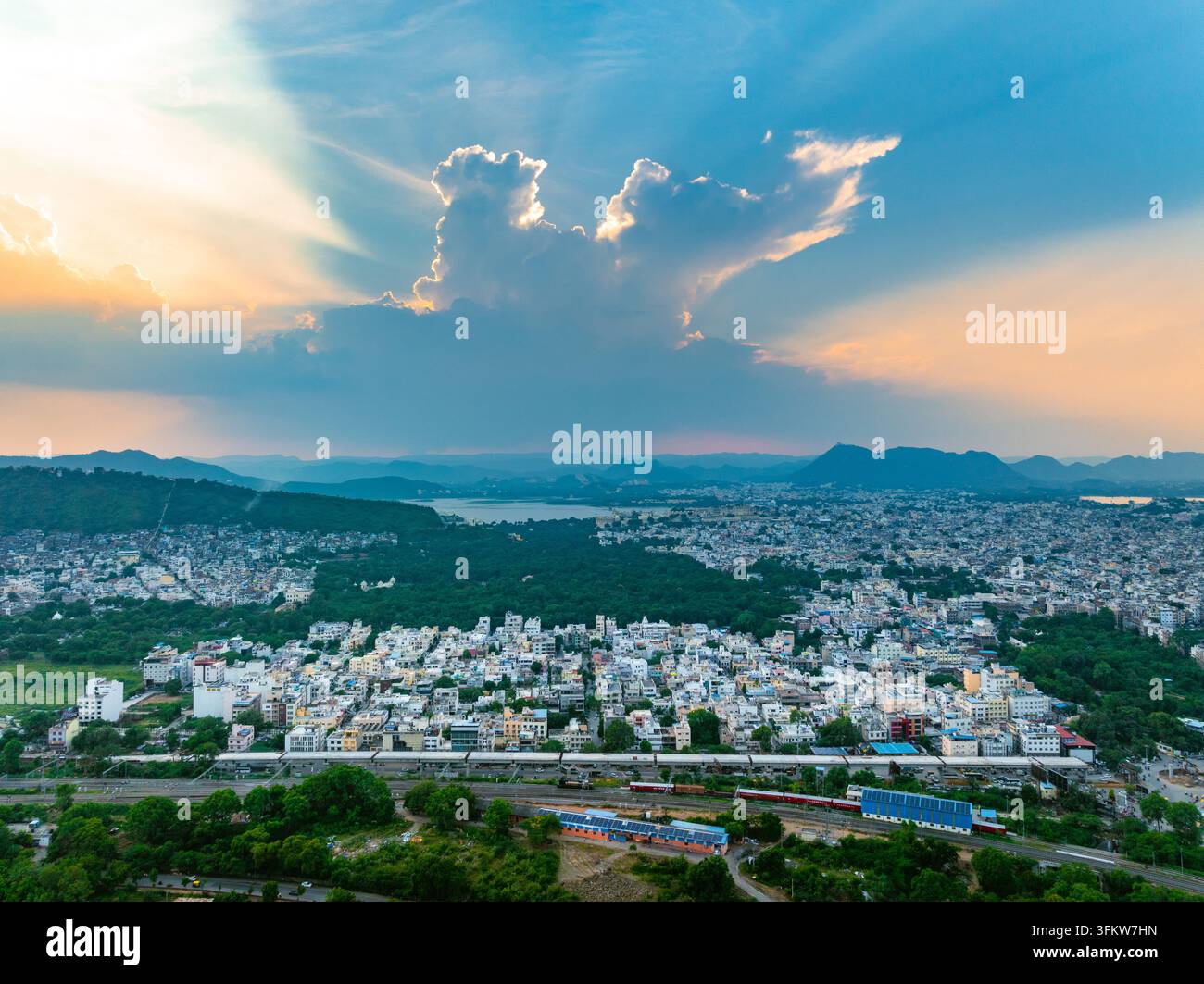 Aerial view of the cityscape with lush green hills, a serene lake in ...