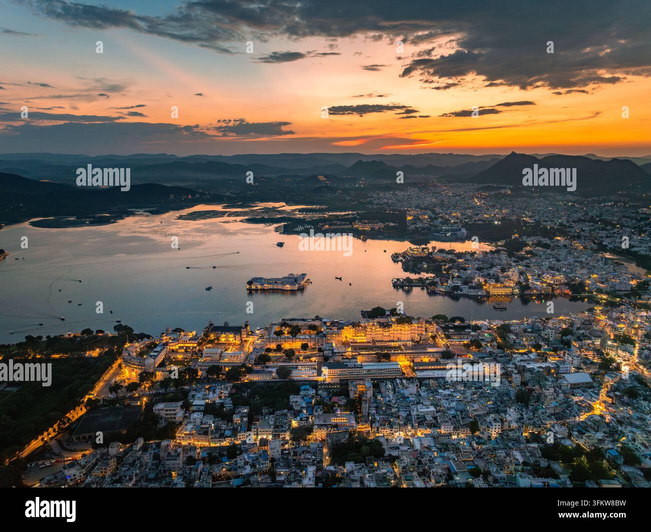 Aerial view of the illuminated City Palace and Lake Pichola at sunset ...