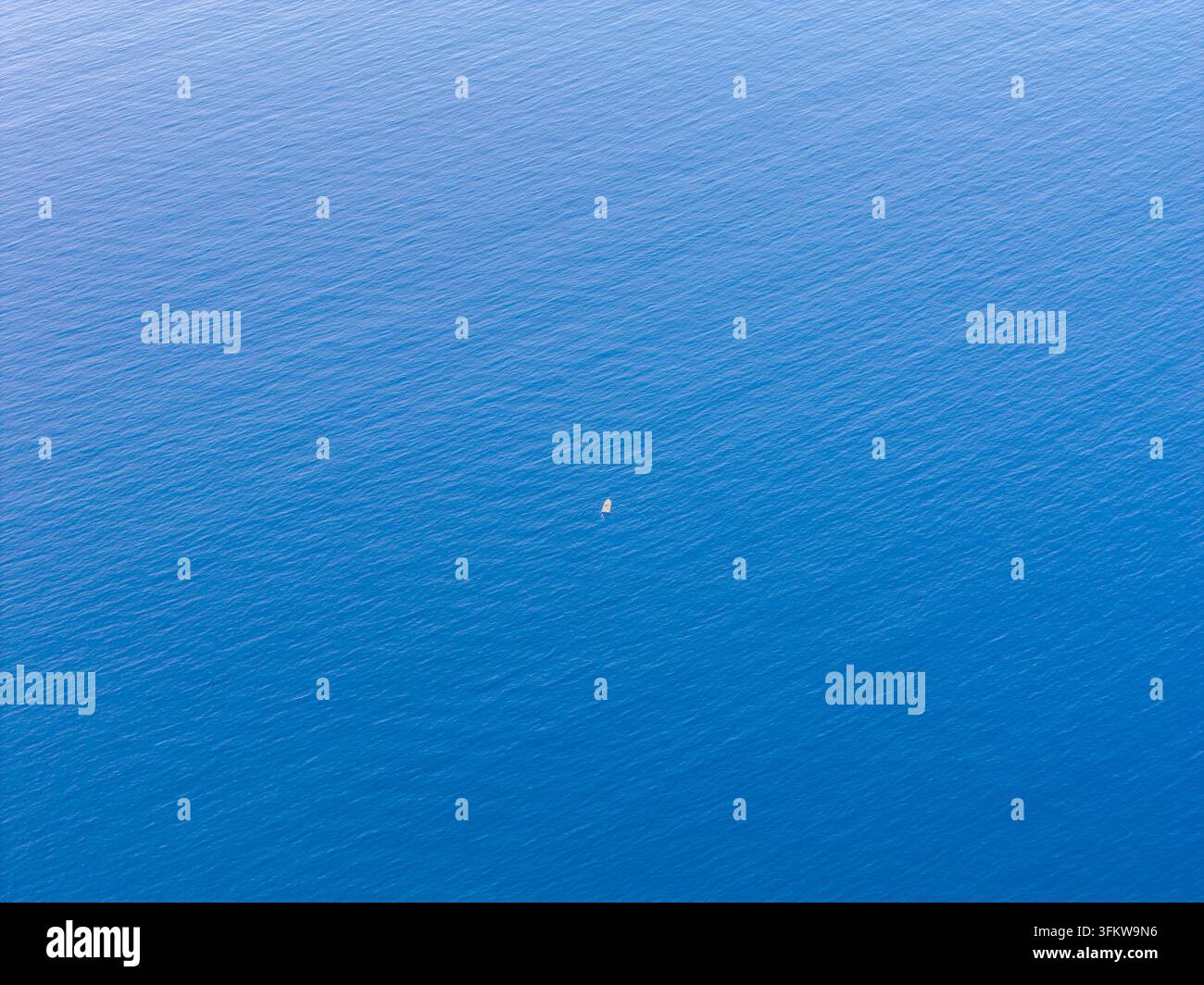 Aerial view of a small boat floating in the vast blue waters of the ...