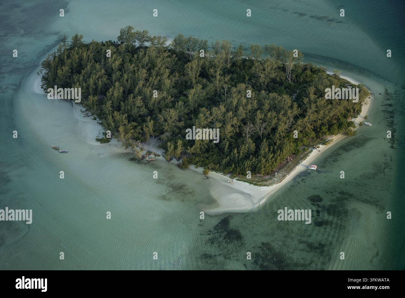 Aerial view of a small tropical island with dense forest and white ...