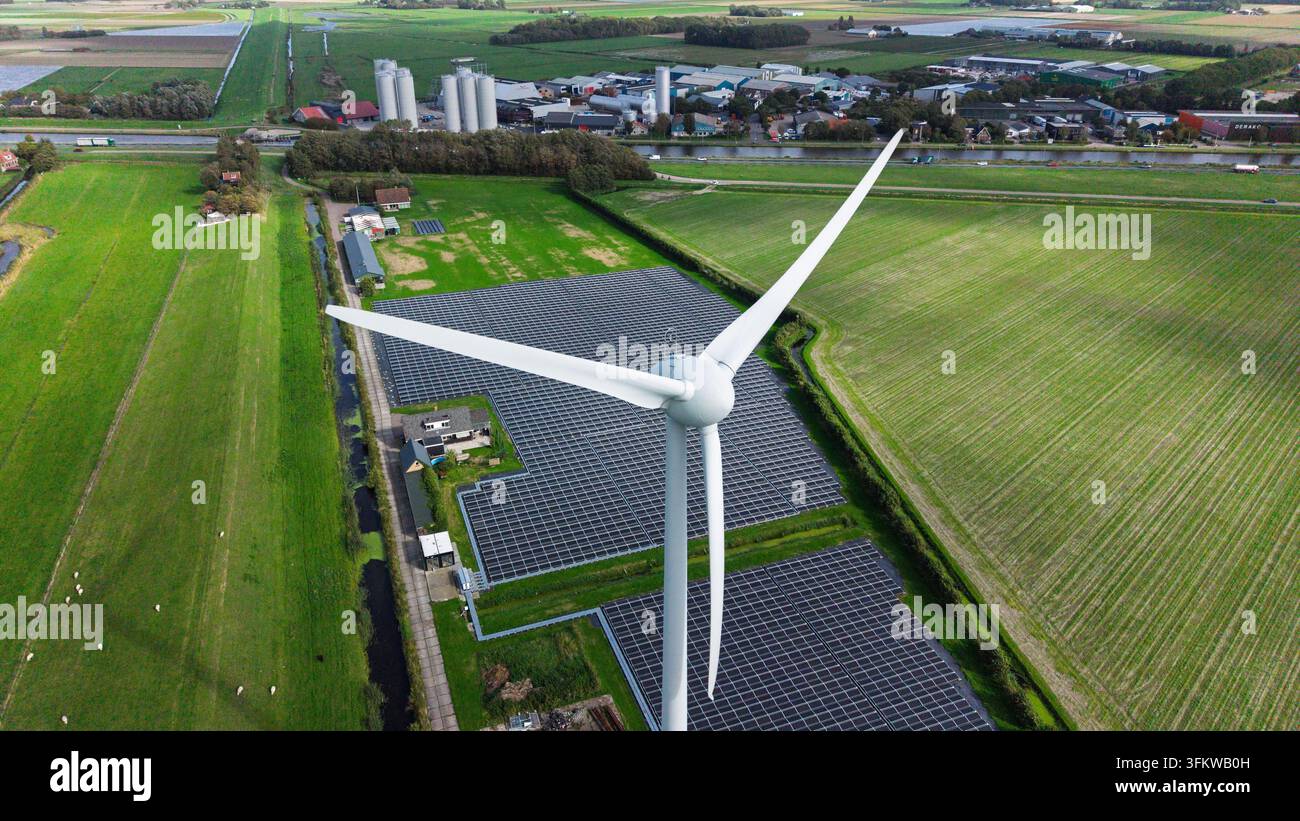 Aerial view of a wind turbine and a large solar panel array situated in ...