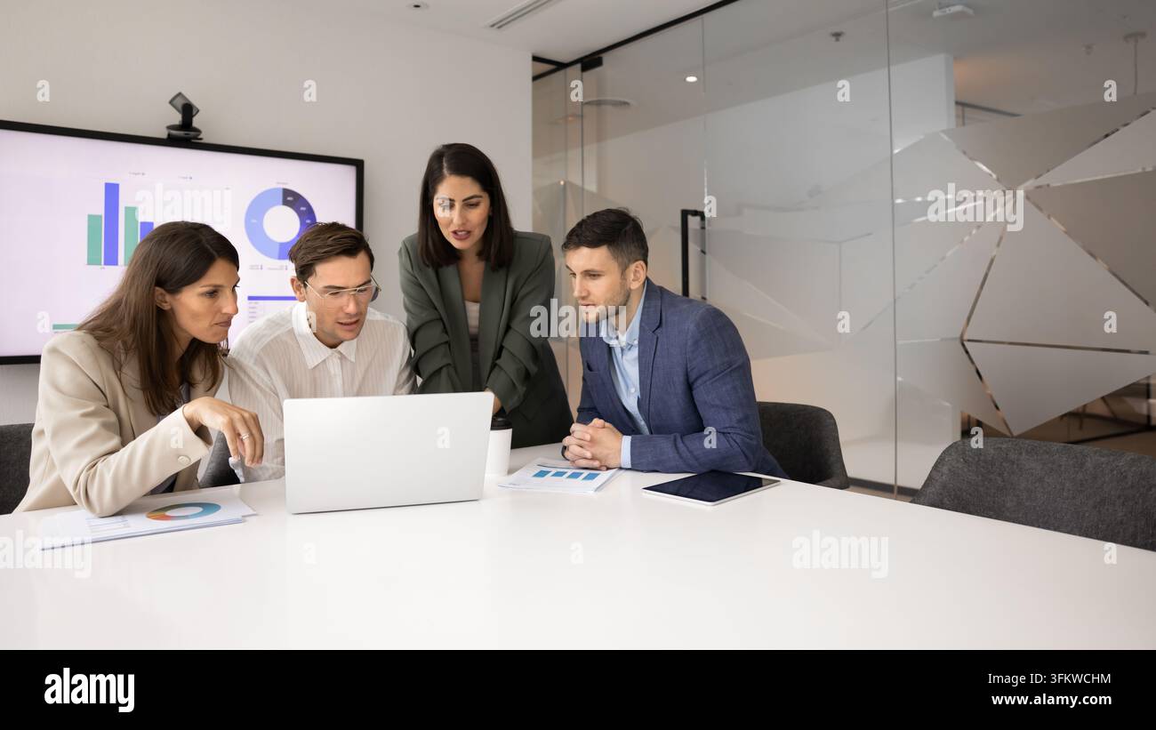 Corporate staff collaborating on digital project using laptop at boardroom Stock Photo