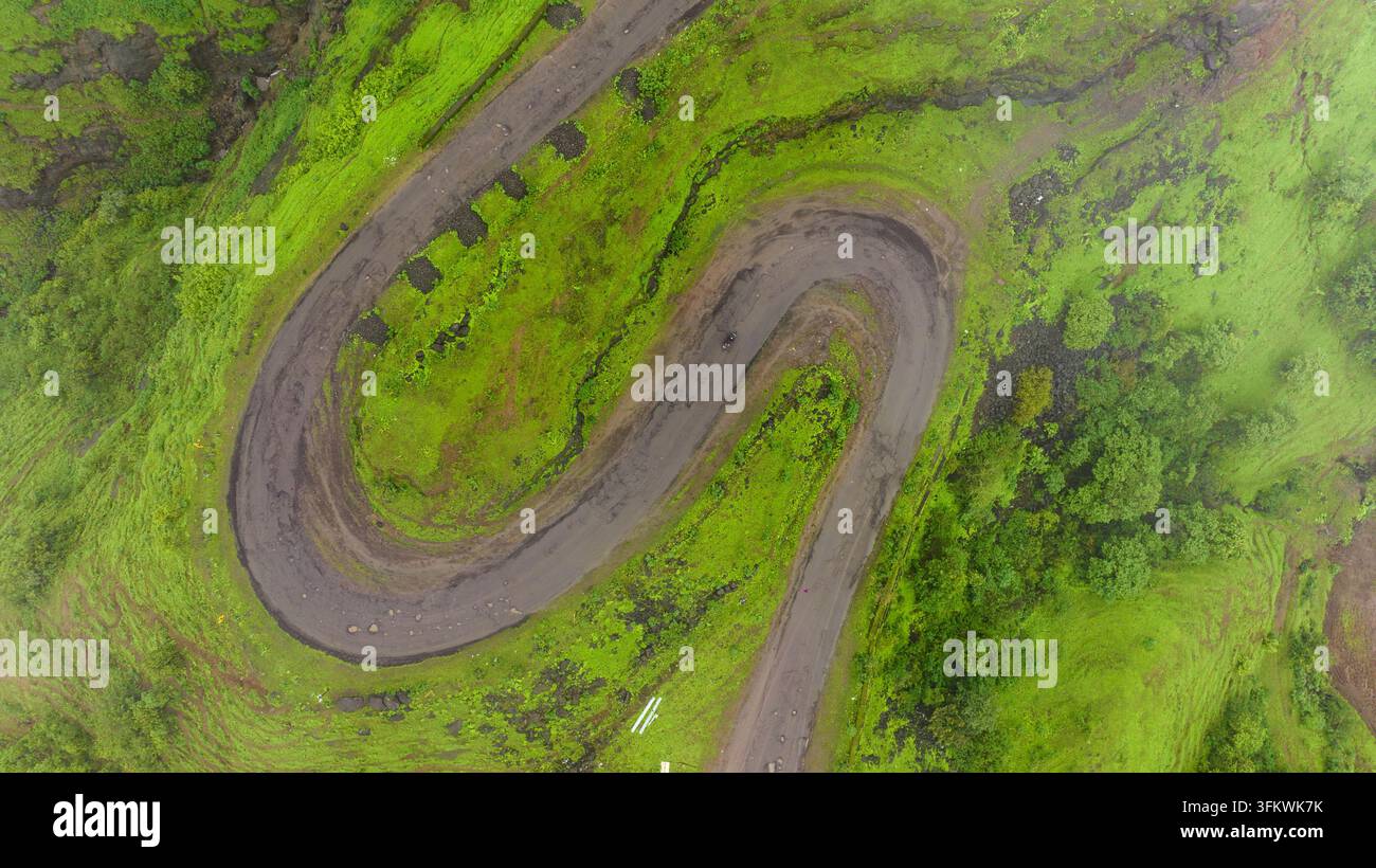 Aerial view of a winding serpentine road cutting through the lush green ...