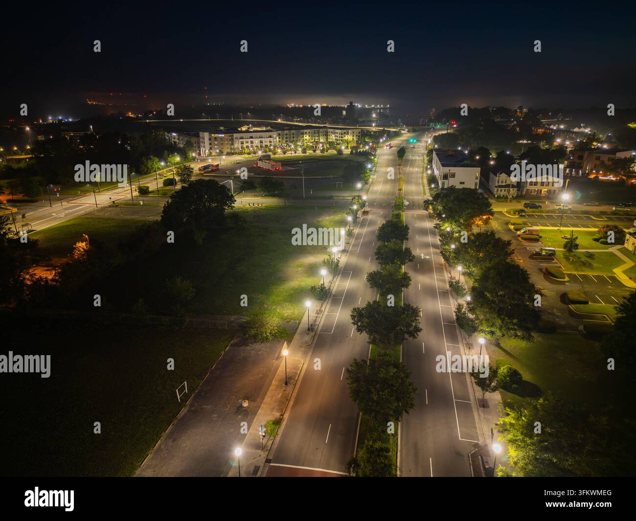 Aerial view of a quiet city street illuminated by streetlights at night ...