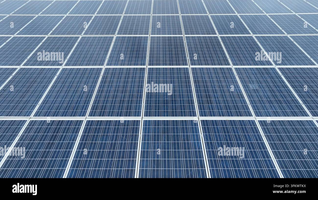 Aerial view of a large array of blue photovoltaic solar panels arranged ...