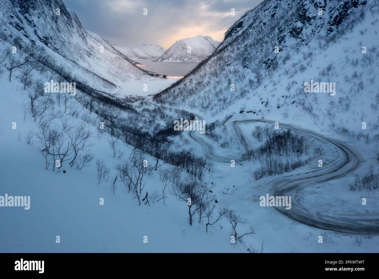 Aerial view of a winding road snaking through a snow-covered mountain ...