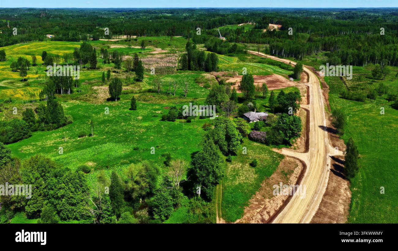 Aerial view of a dirt maintenance road winding through a lush green ...