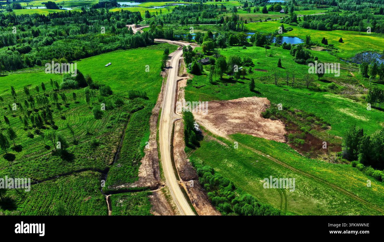 Aerial view of a dirt maintenance road winding through a lush green ...