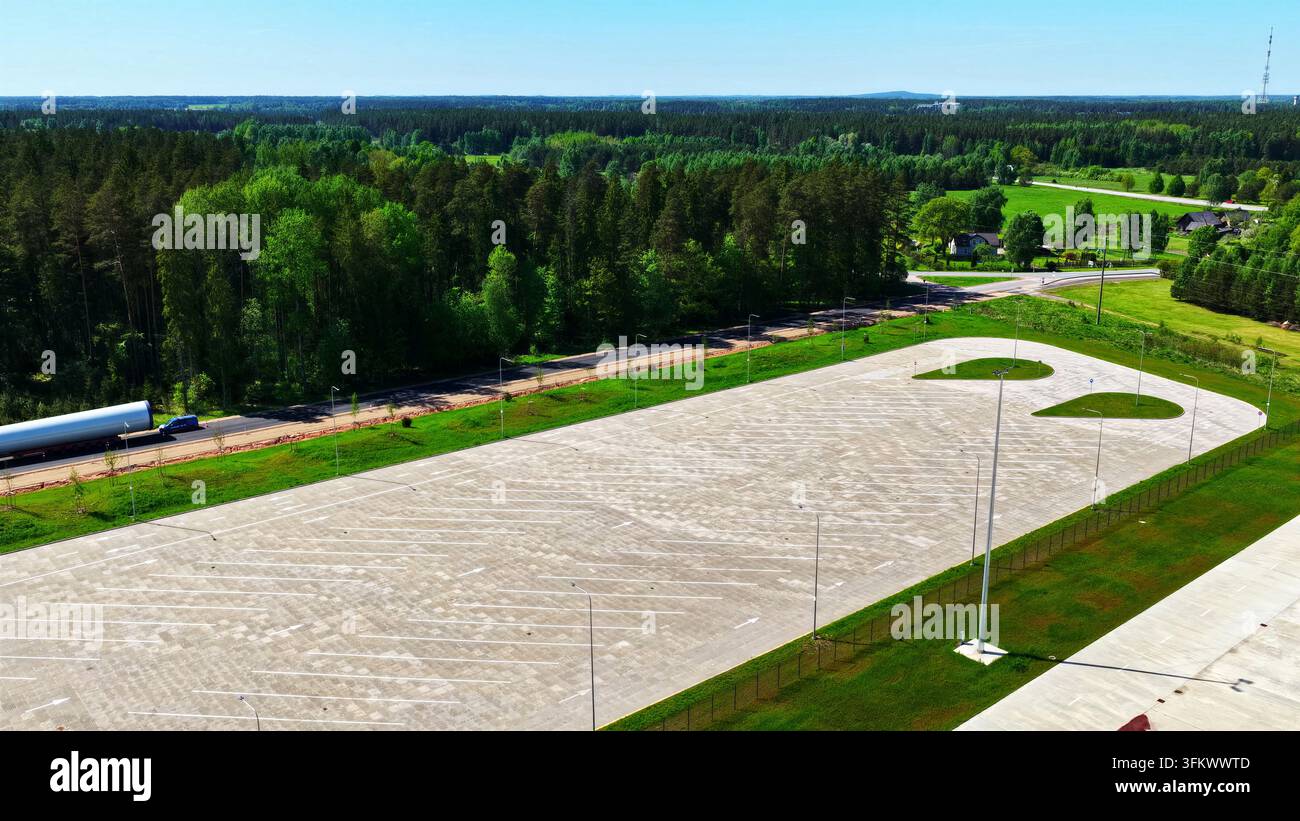 Aerial view of an empty paved parking lot surrounded by lush green ...