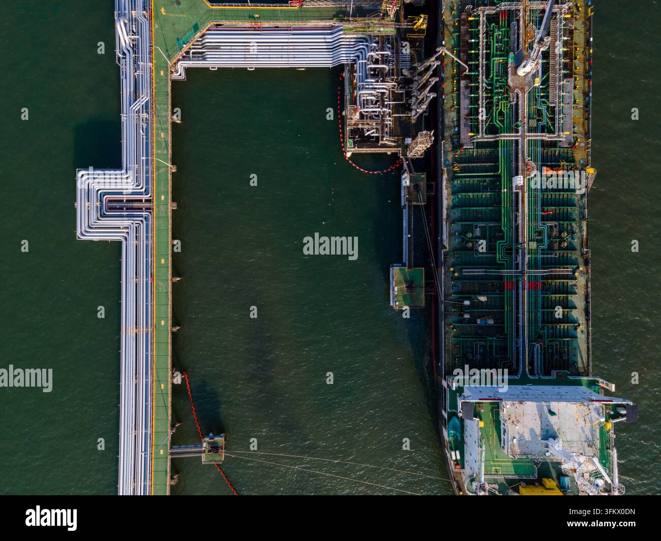 Aerial view of an oil tanker docked at a terminal with industrial ...