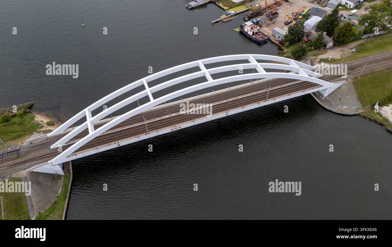 Aerial view of a modern white railway arch bridge spanning over a river ...