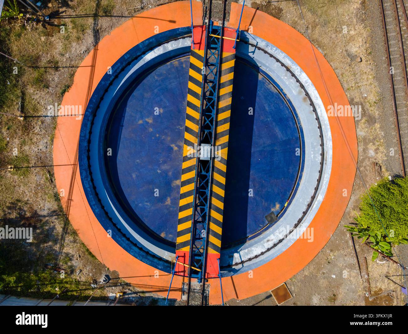 Aerial view of a railway turntable with a blue circular base, an orange ...