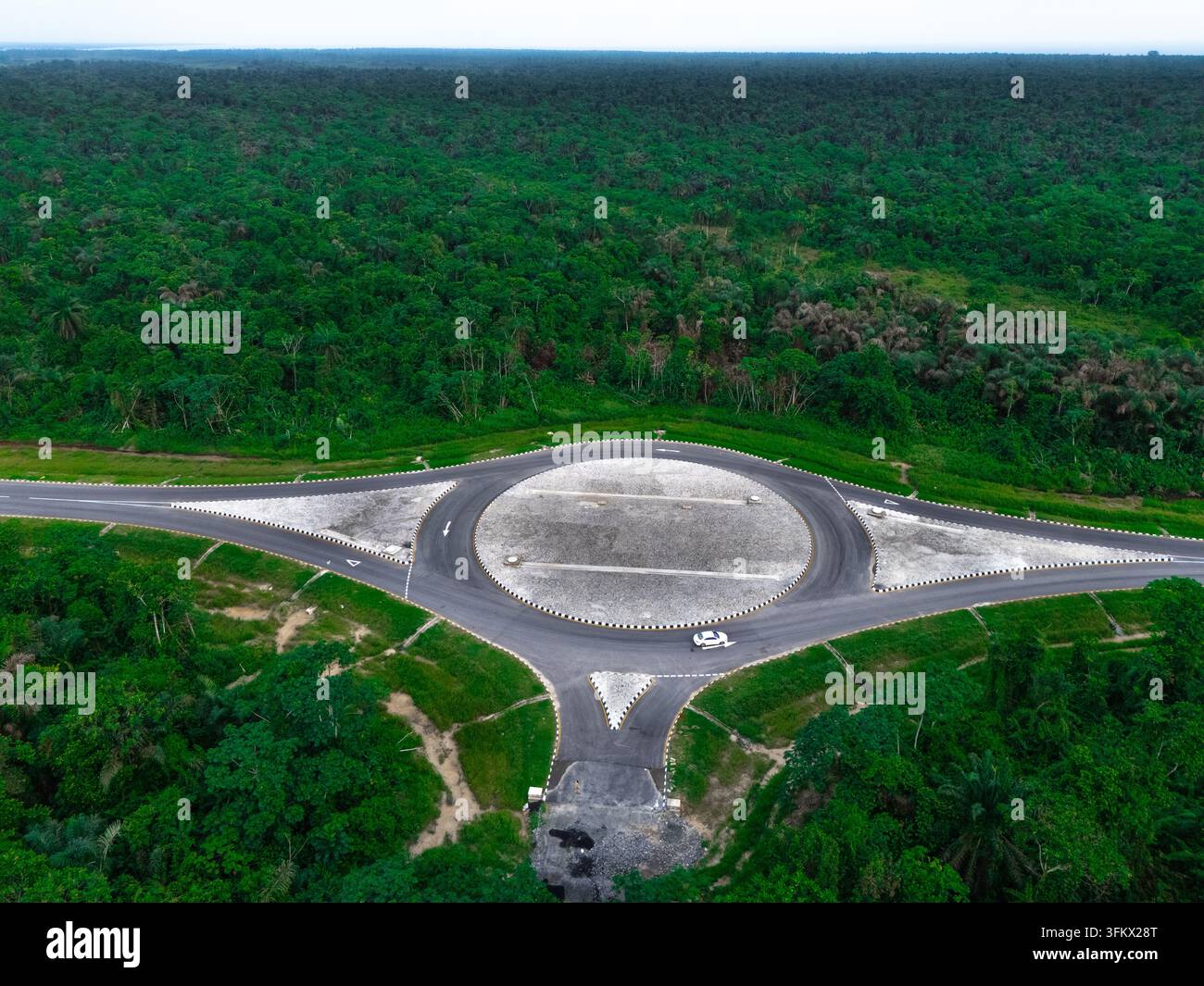 Aerial view of a roundabout on a road surrounded by dense tropical ...