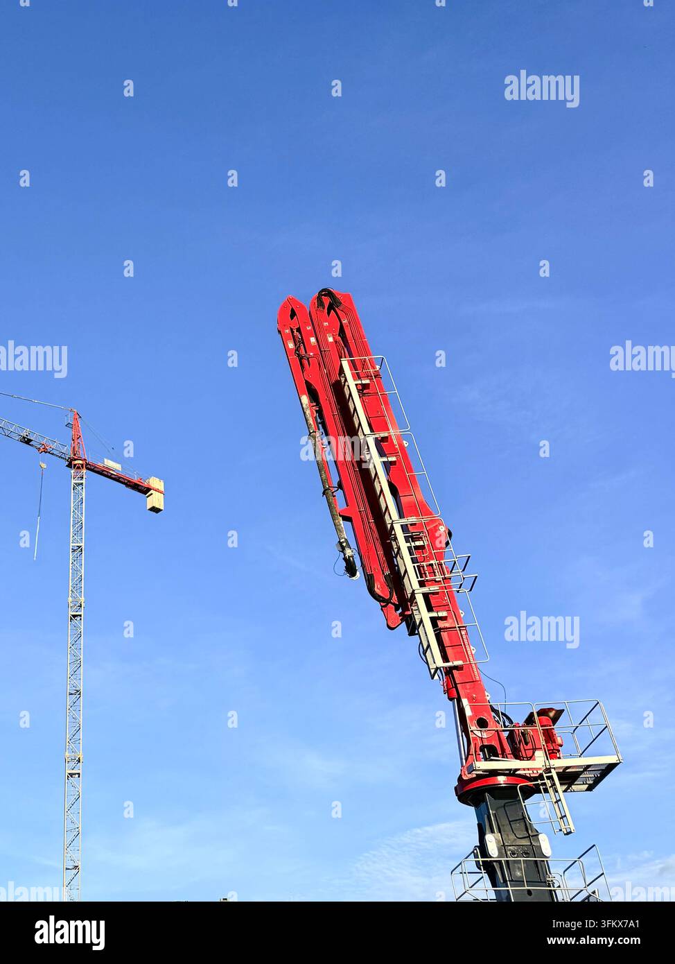 Tower cranes at a construction site against a clear blue sky. Industrial development and machinery concept. Stock Photo