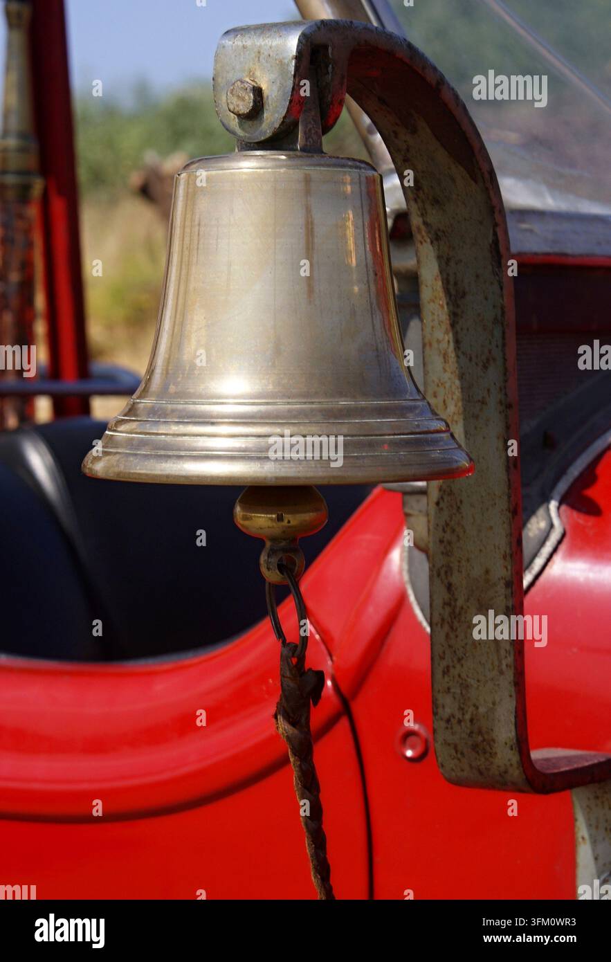 Shiny brass bell mounted on a classic red fire engine Stock Photo