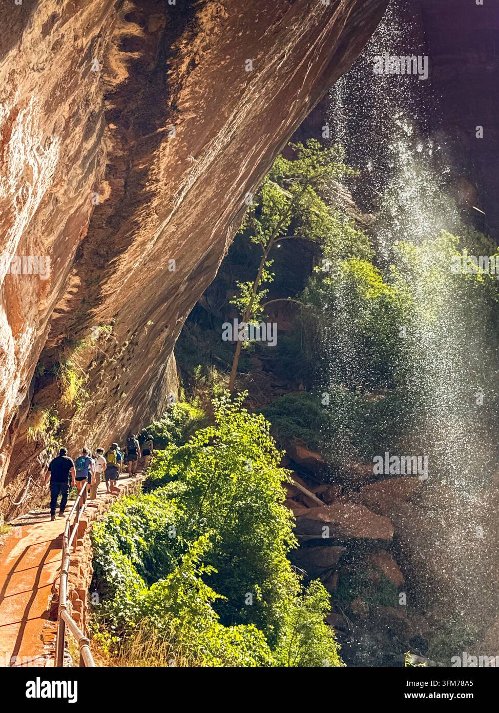 Zion National Park, Utah, USA - 27 June 2026: People walking along a narrow path under water falling from a rock face in Zion National Park. - Smartphone Captured Stock Image