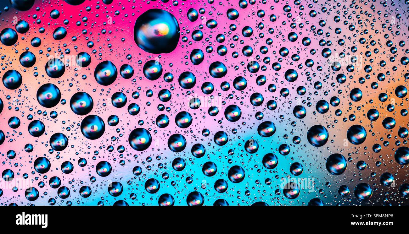 Water drops creating a bright and colorful abstract background with gradients of pink, blue, and orange, showing natural moisture Stock Photo