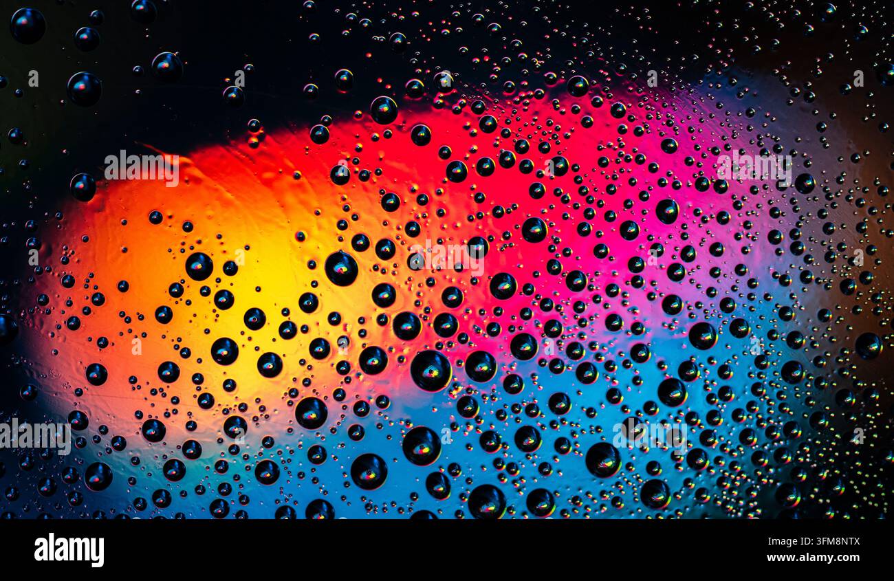 Water drops creating a dynamic abstract pattern, reflecting and refracting a vivid rainbow gradient with soft bokeh Stock Photo