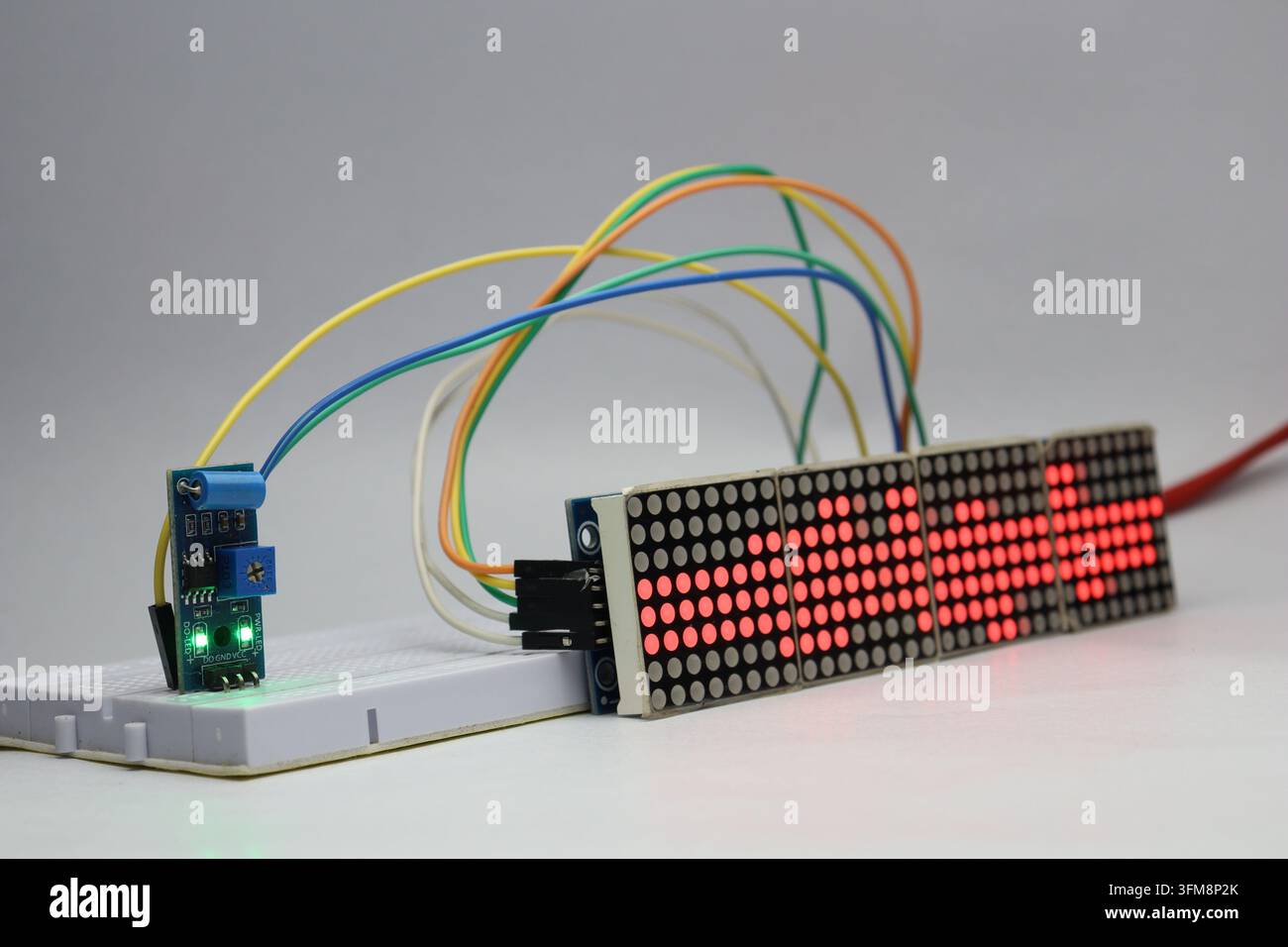 Red dot matrix display module and vibration sensor connected on a breadboard displaying various patterns Stock Photo