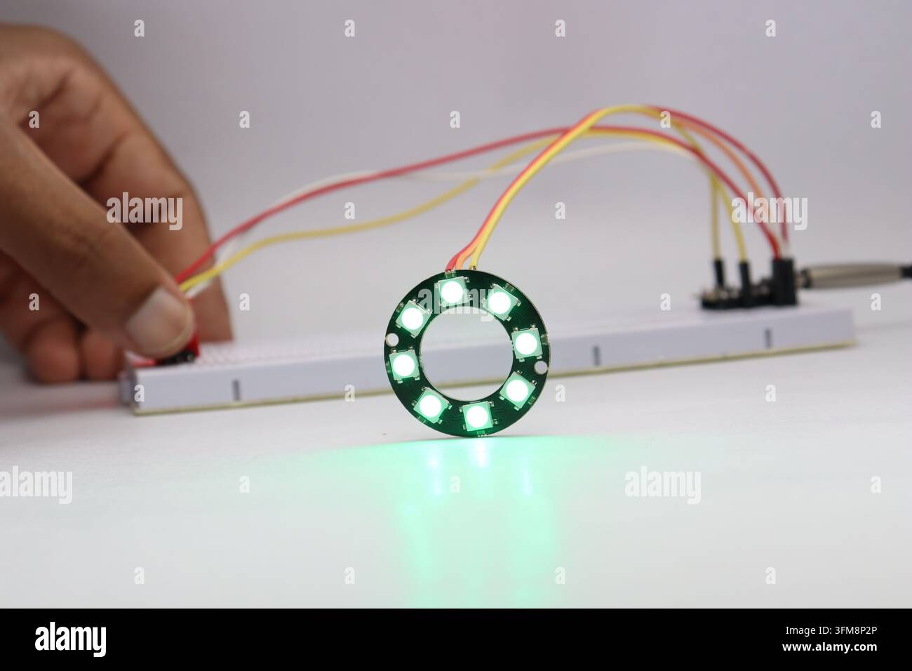 ARGB LED ring light glowing in color controlled by a sensor and microcontroller in the background Stock Photo