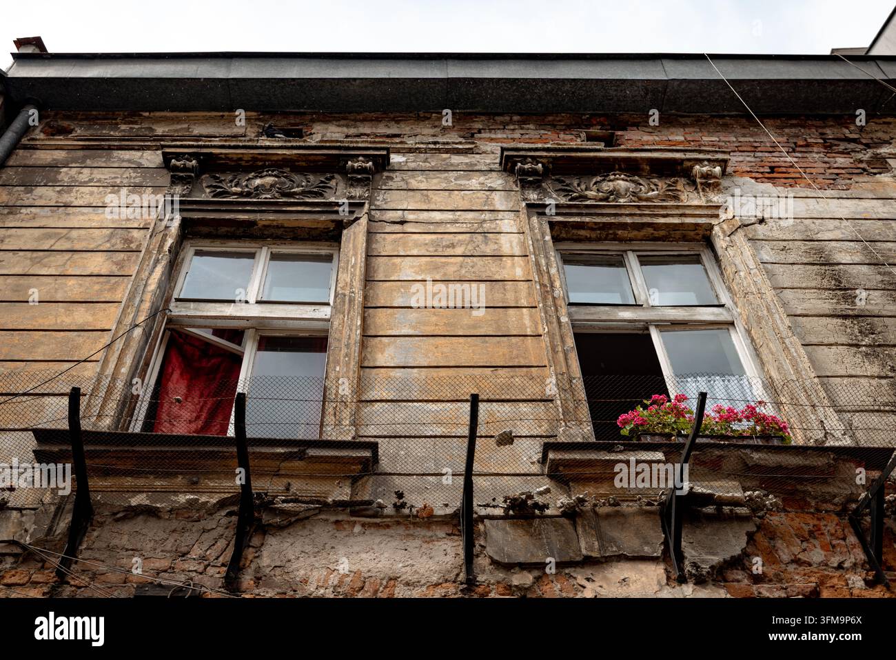 Crumbling plaster and exposed brickwork on a weathered historic tenement in Kazimierz. Stock Photo