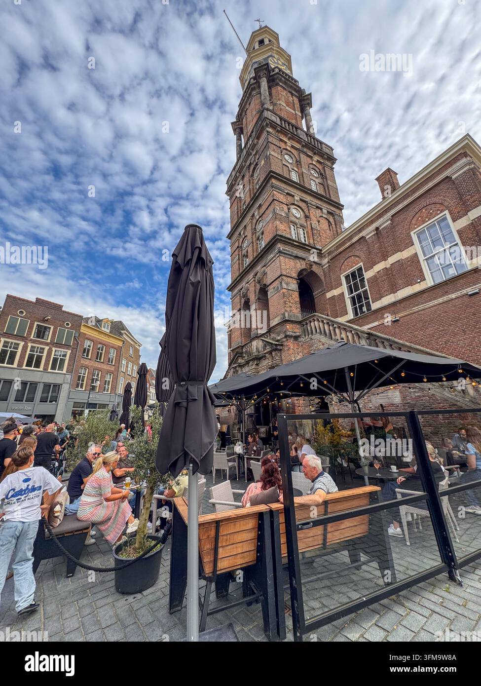 ZUTPHEN, NETHERLANDS - SEPTEMBER 27, 2026: Visitors relax at crowded outdoor terraces beneath the historic Wijnhuistoren on Groenmarkt. - Smartphone Captured Stock Image