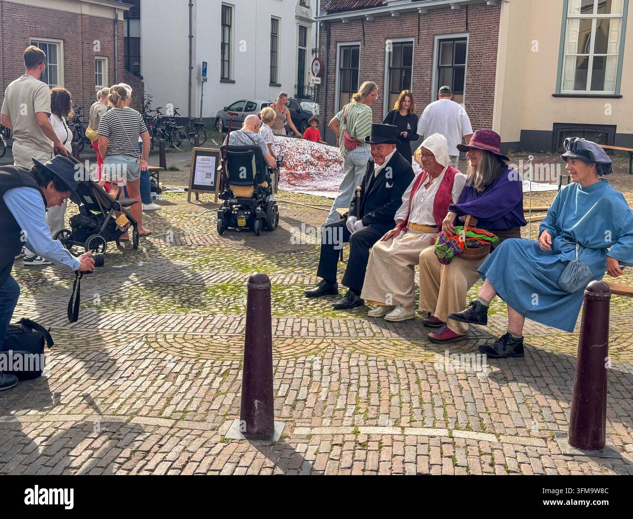 ZUTPHEN, NETHERLANDS - SEPTEMBER 27, 2026: Costumed participants dressed in historical period clothing pose for a photographer on a cobblestone street. - Smartphone Captured Stock Image