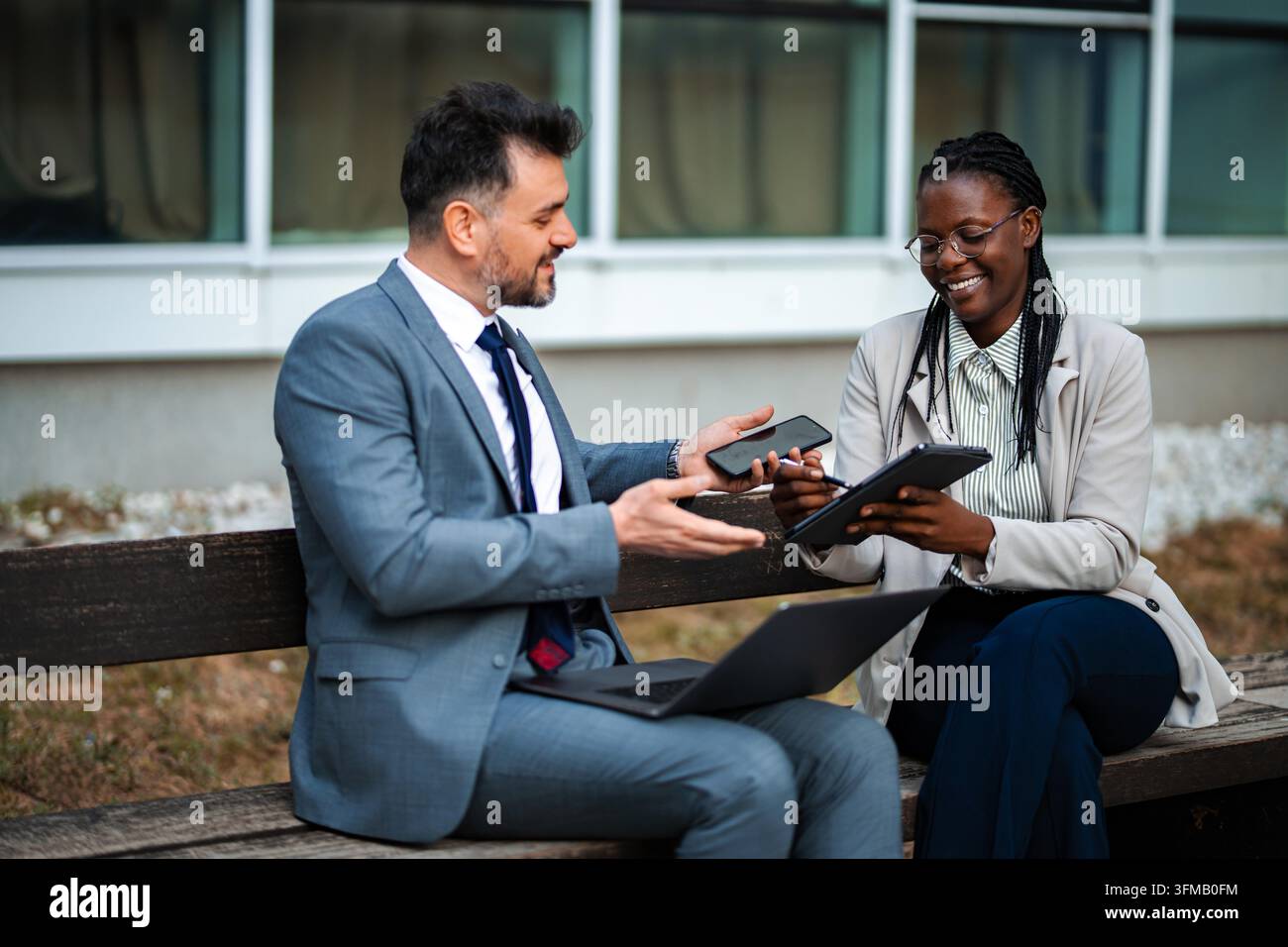 Business colleagues collaborating outdoors using digital tablet and smartphone Stock Photo
