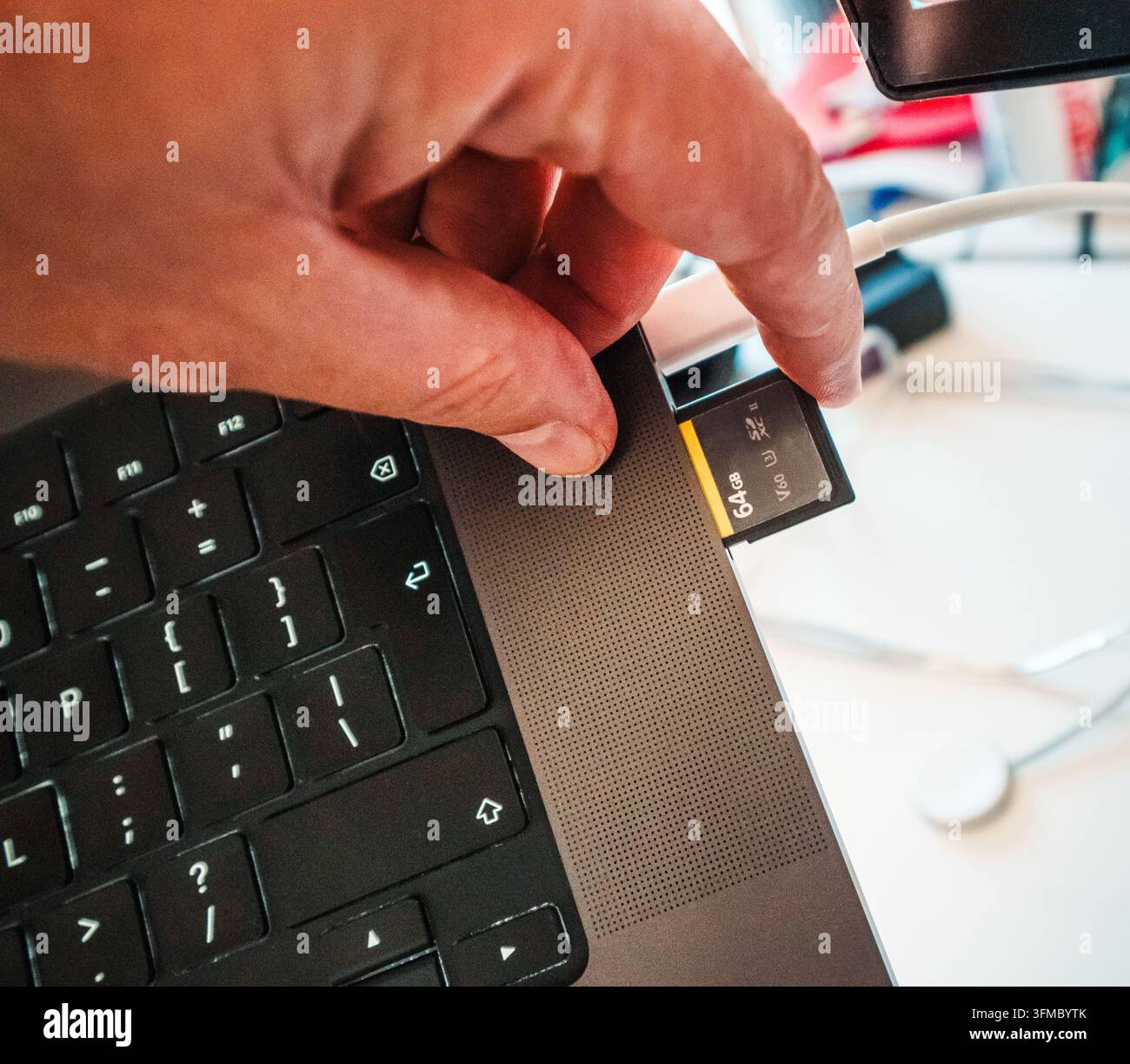 Inserting high speed SD memory card laptop slot data transfer offload backup. A close-up shot of a photographer or videographer inserting a high-perfo Stock Photo