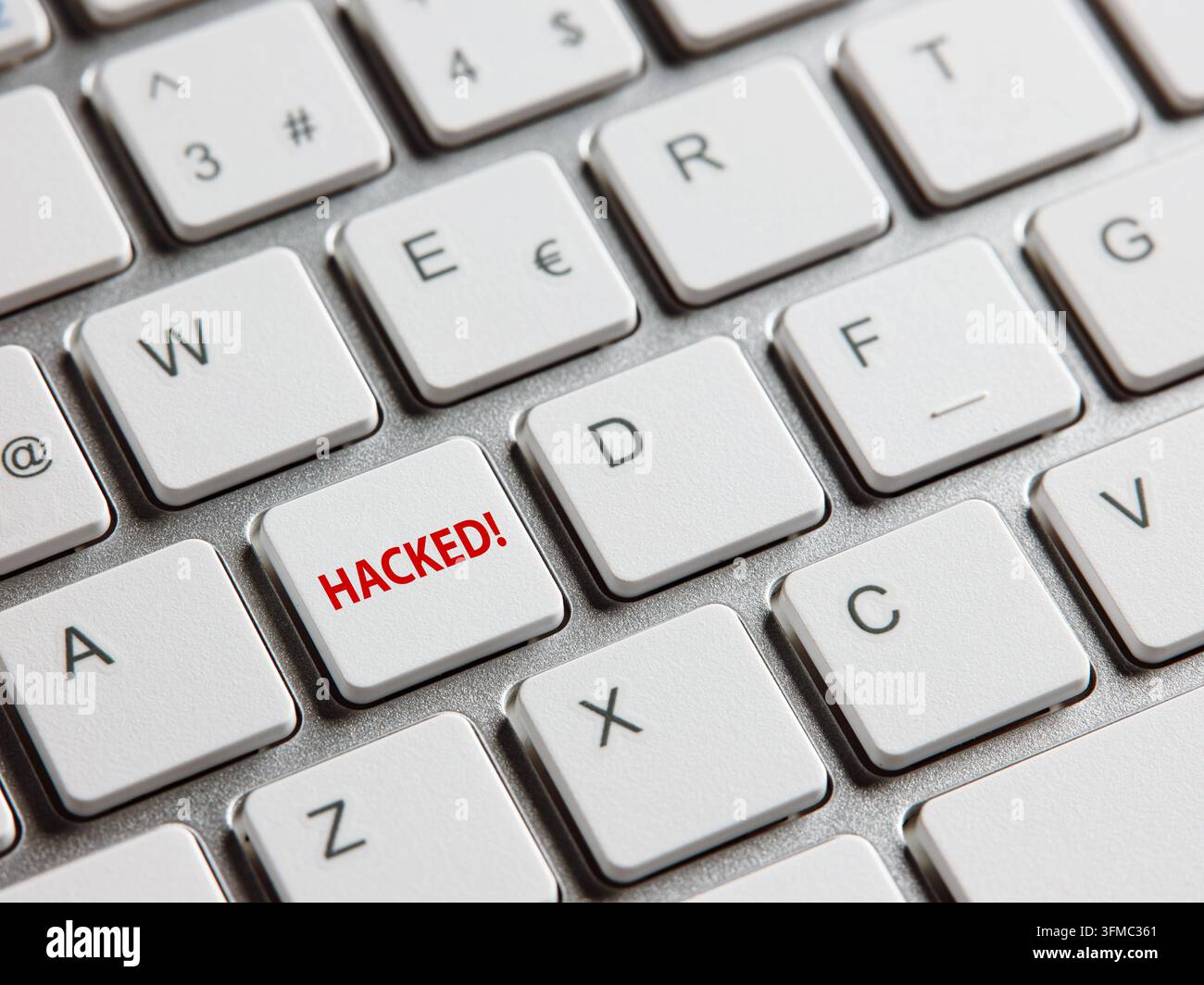 Computer keyboard showing a red HACKED key, symbolizing data breach, cyber attack, and internet vulnerability Stock Photo
