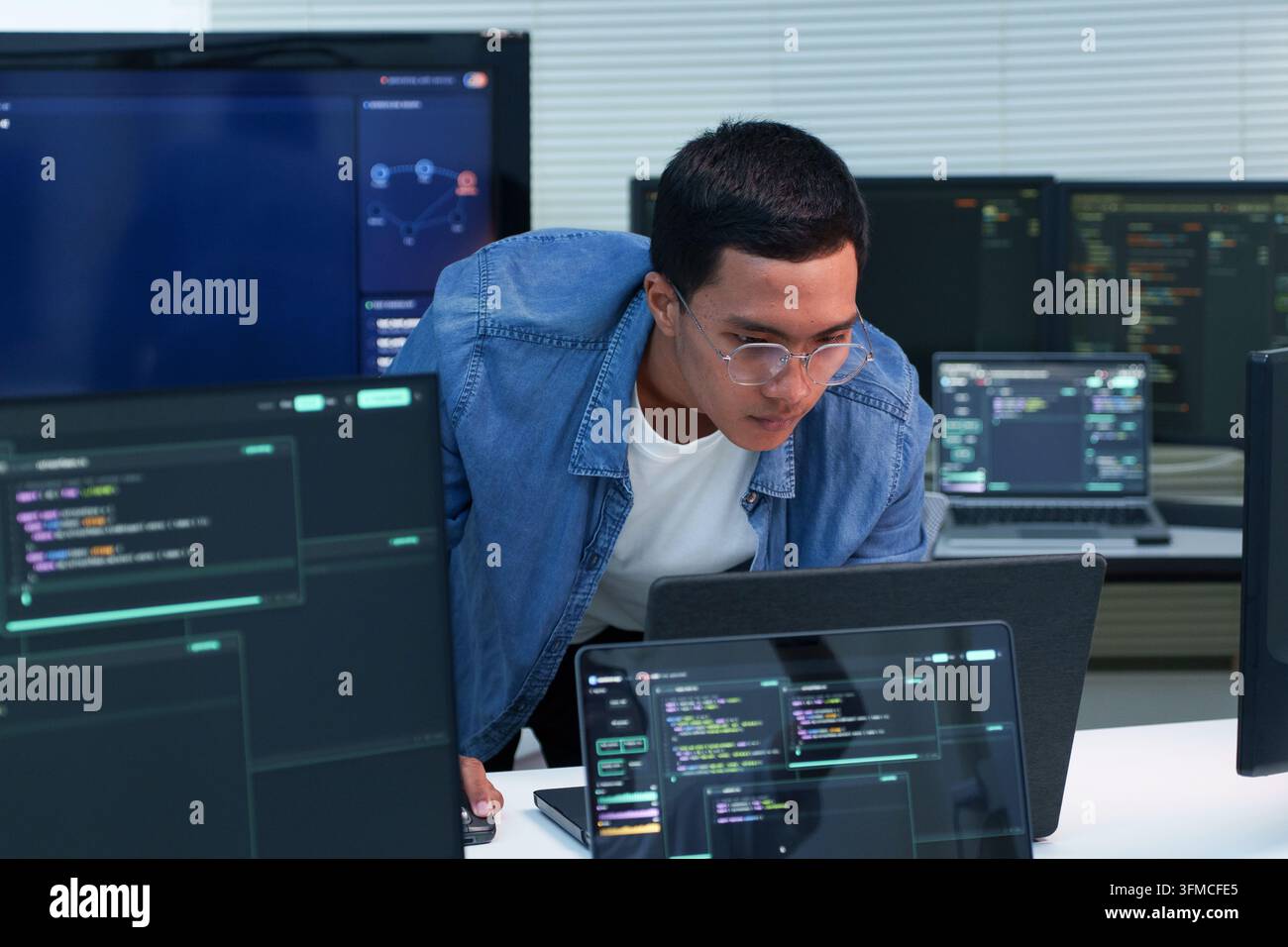 Programmer working with software code on multiple screens, representing digital development, artificial intelligence, cybersecurity, and modern techno Stock Photo