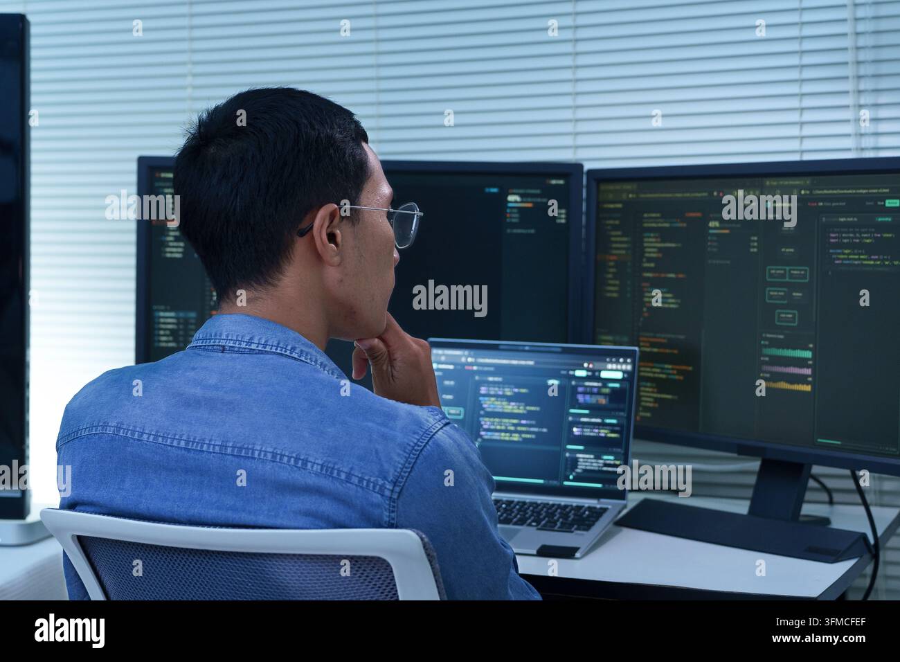 Programmer Developing Software with Multiple Code Screens Stock Photo
