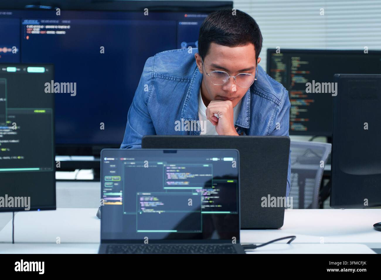 Focused programmer working on software development, digital technology, artificial intelligence, and cybersecurity code using a laptop. Stock Photo