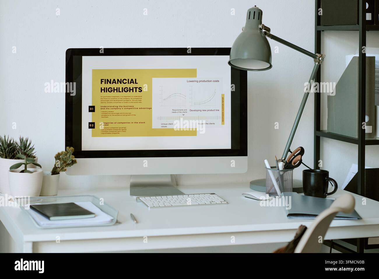 Computer Displaying Financial Presentation on Desk in Office Stock Photo