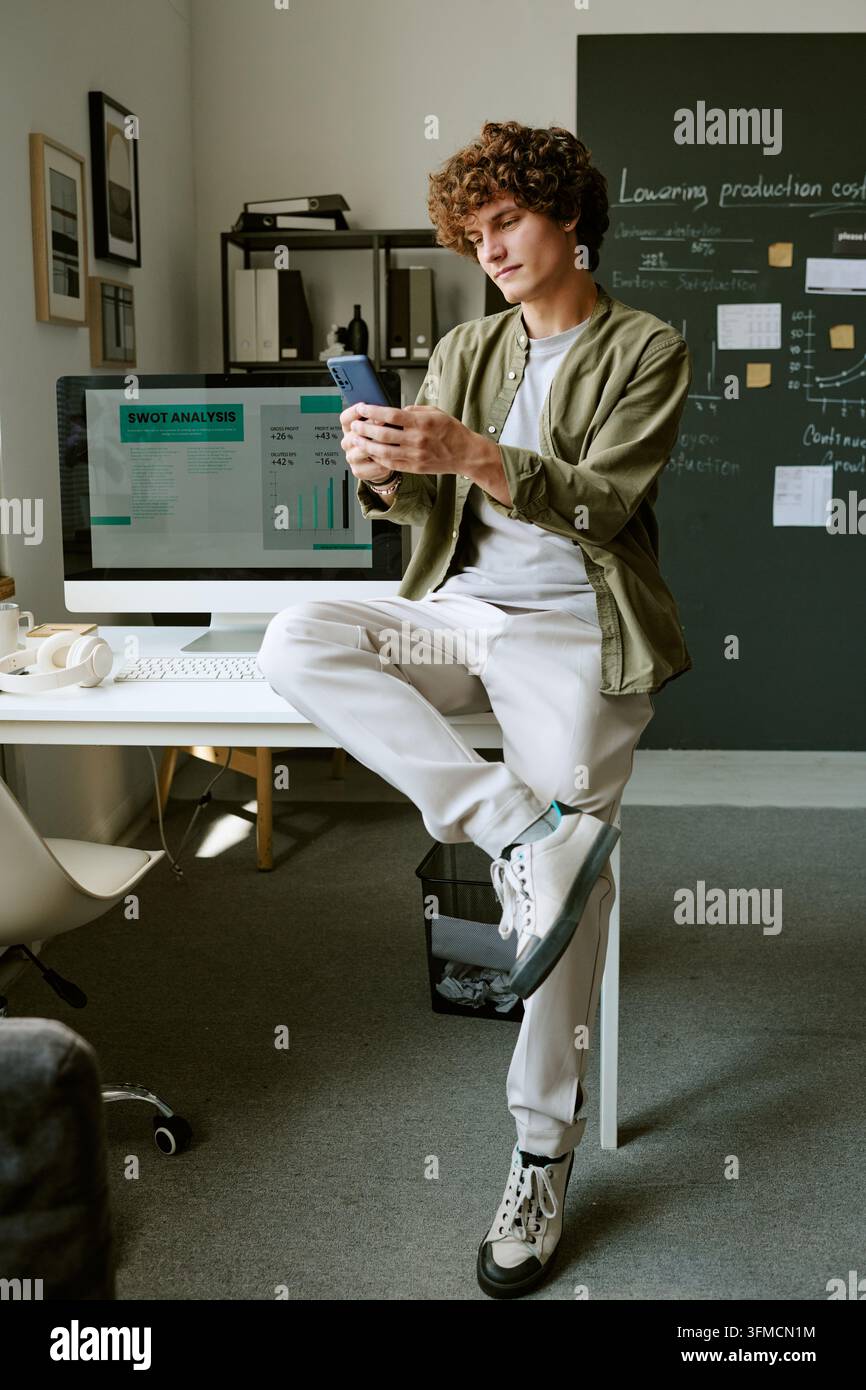 Man Using Smartphone by Desk in Creative Modern Office Stock Photo