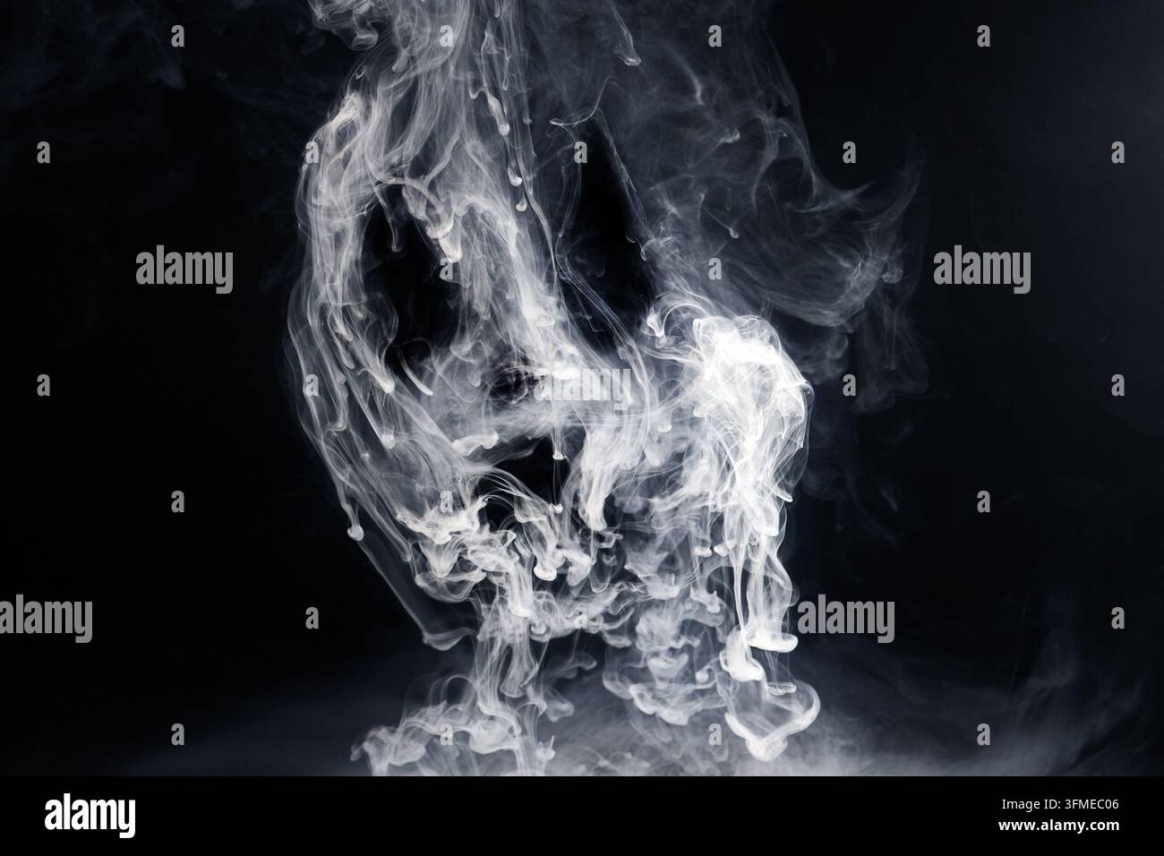 White smoke dissolving in dark water Stock Photo