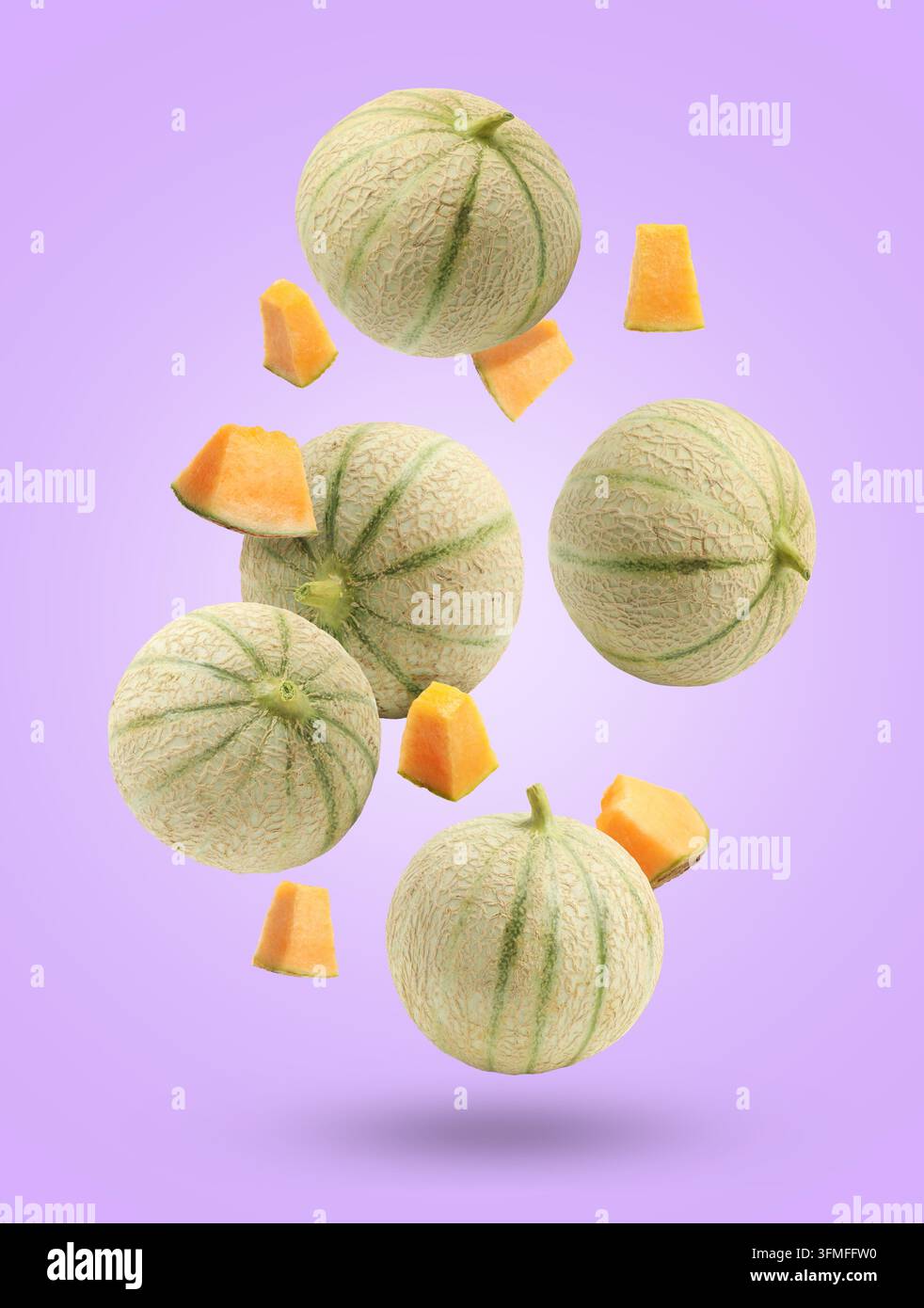 Fresh cantaloupe melons falling on violet background. Whole and sliced Stock Photo
