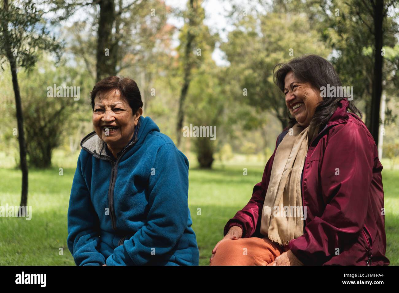 Two senior women friends laughing together while having a conversation outdoors Stock Photo