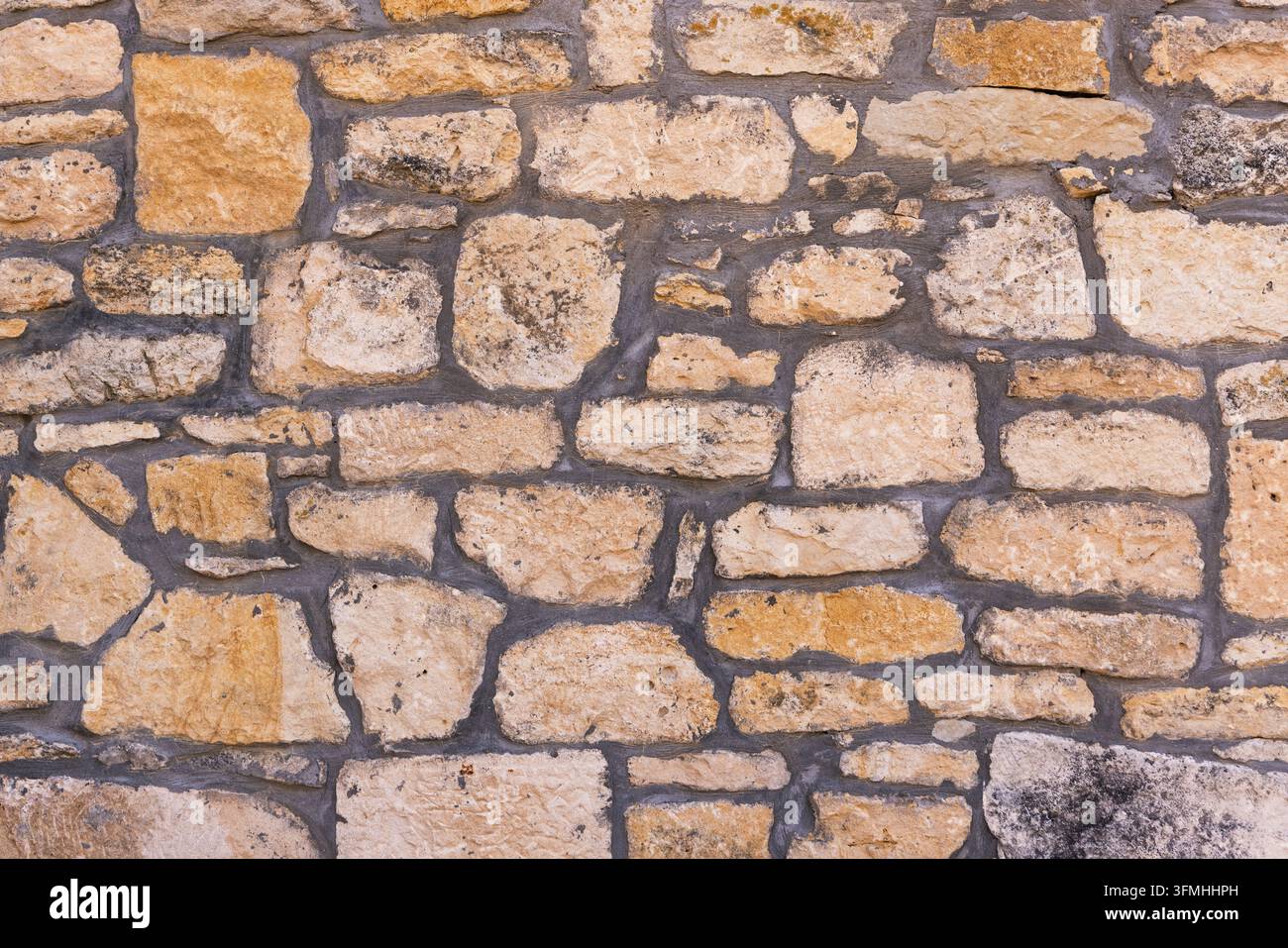 Textured stone wall with dark mortar joints background Stock Photo