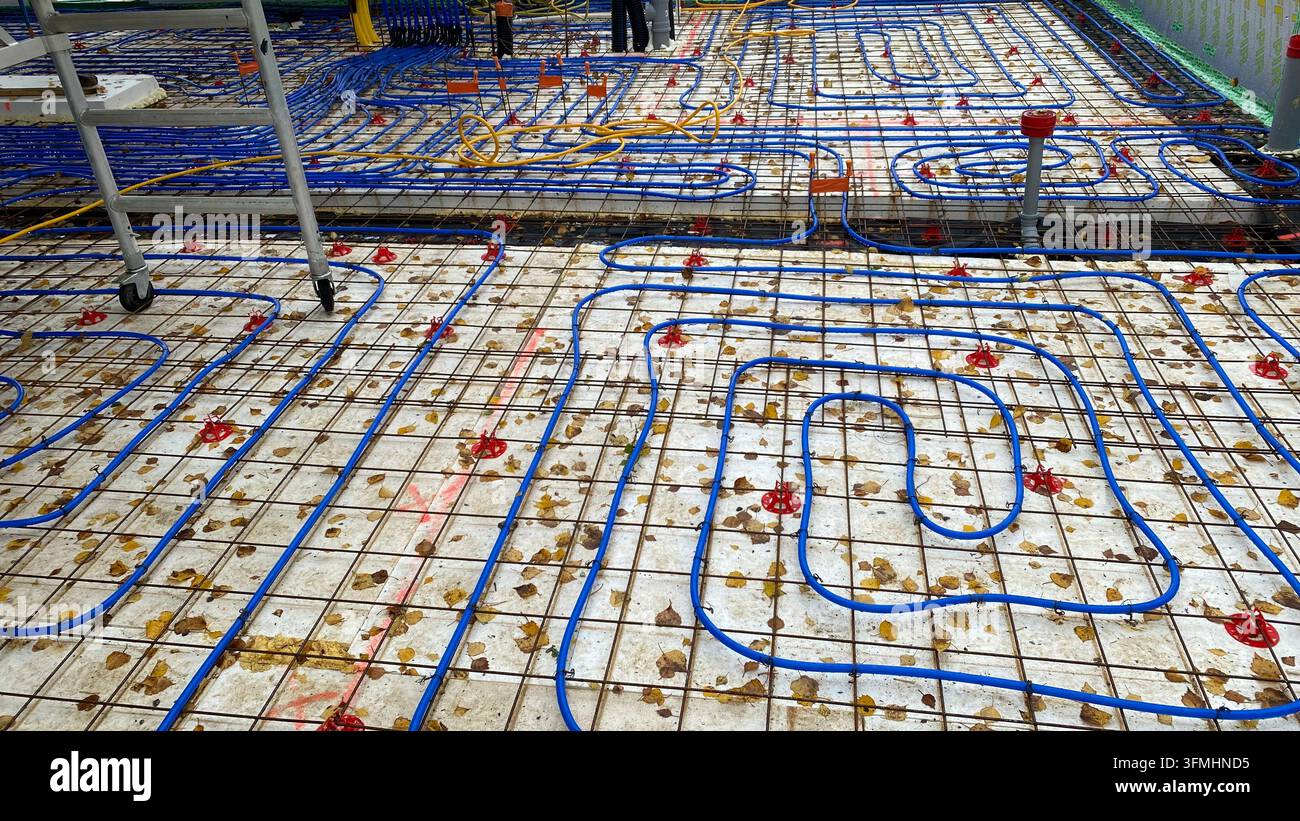 Underfloor heating pipes installed over reinforcement mesh at construction site Stock Photo