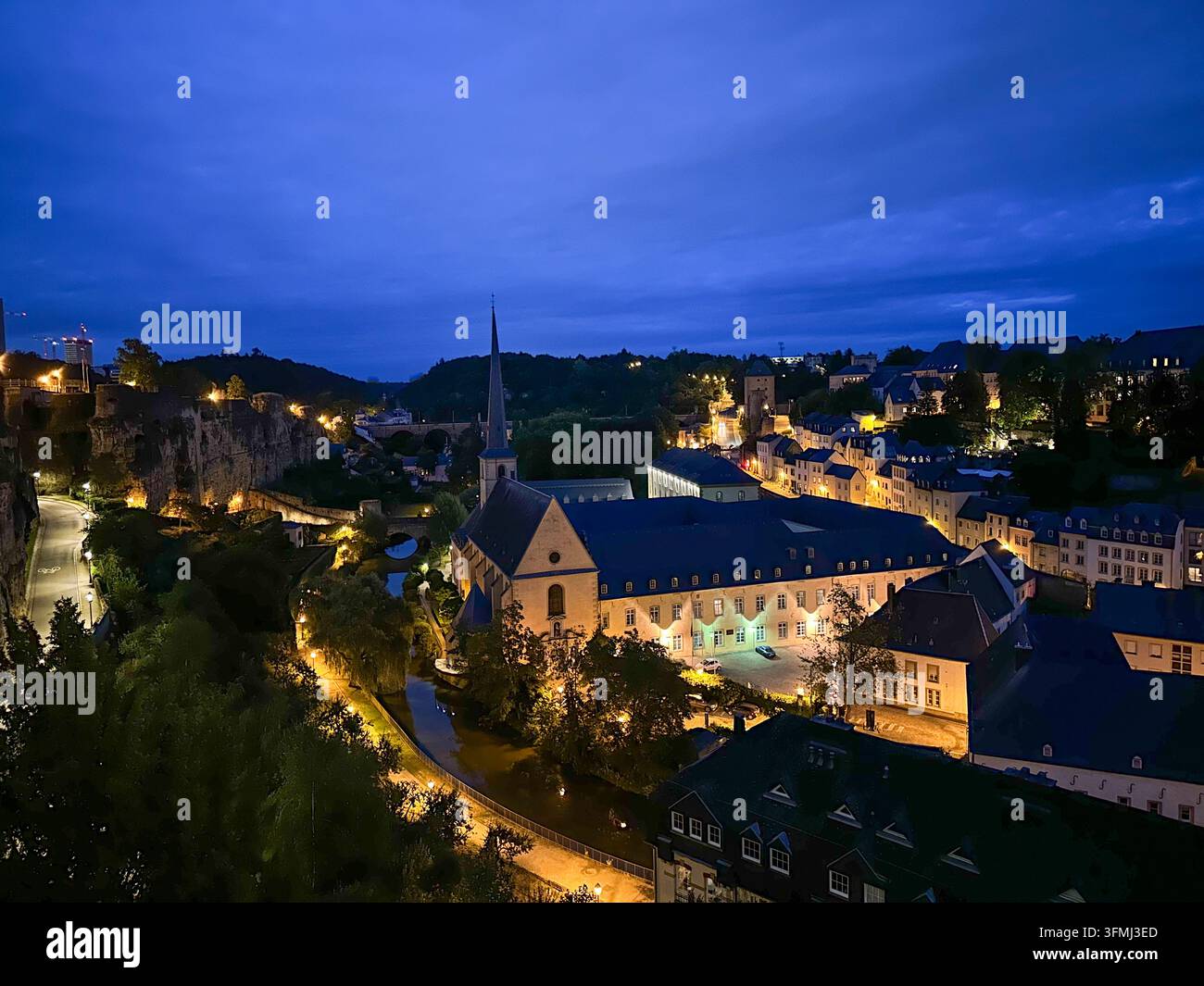 European city landscape with historic church and illuminated buildings at twilight blue hour. High angle view of a historic European town at dusk feat - Smartphone Captured Stock Image