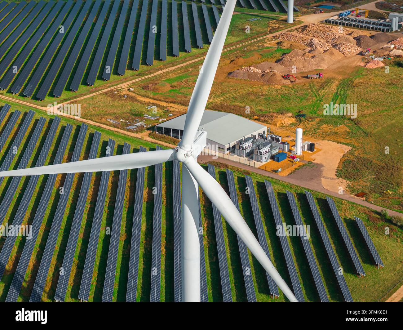 Aerial view of a wind turbine in the foreground and a large solar panel ...