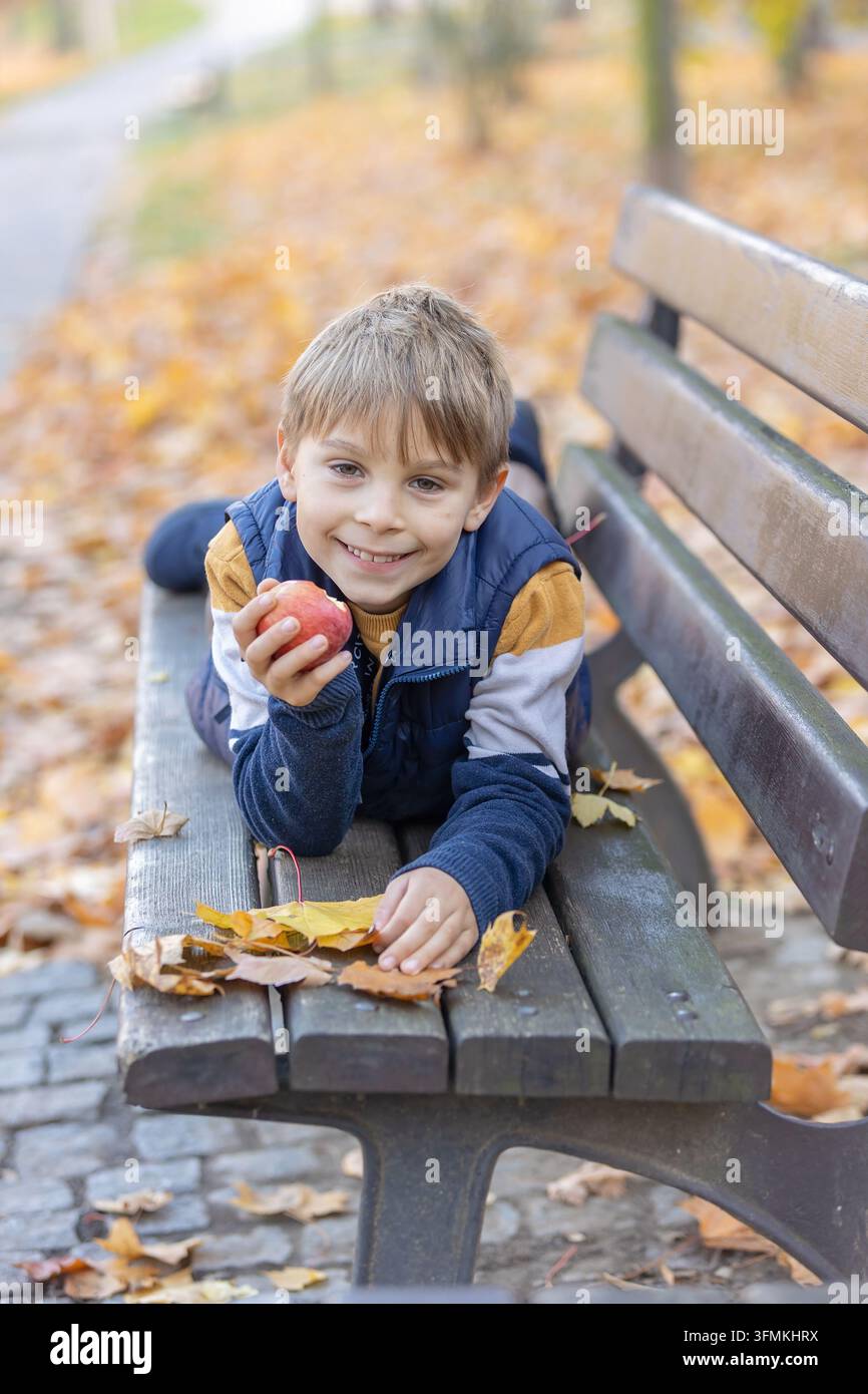 Cute little child, sweet boy in a park, sitting on a bench and in the ...