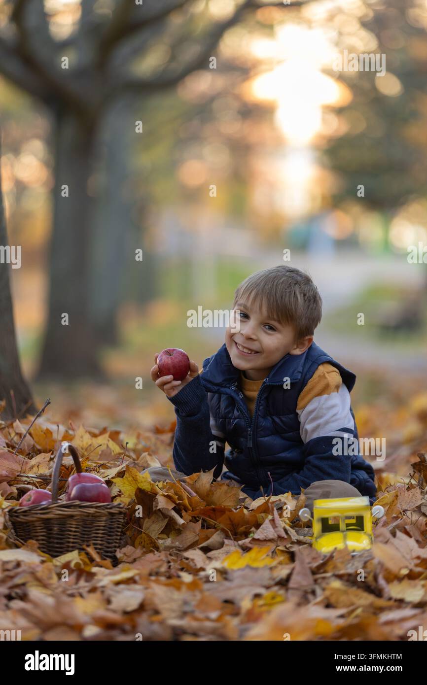 Cute little child, sweet boy in a park, sitting on a bench and in the ...