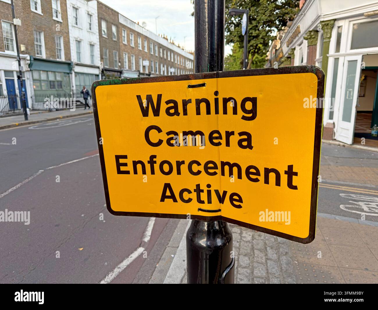 Yellow roadside sign reading Warning Camera Enforcement Active on Caledonian Road in London. Stock Photo