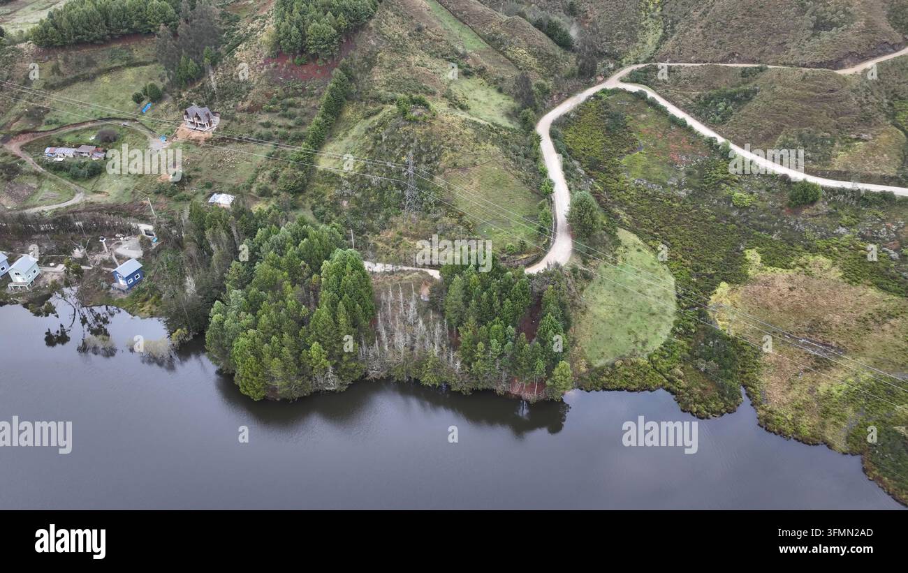 Aerial view of Corani Lake surrounded by lush green hills, a winding ...