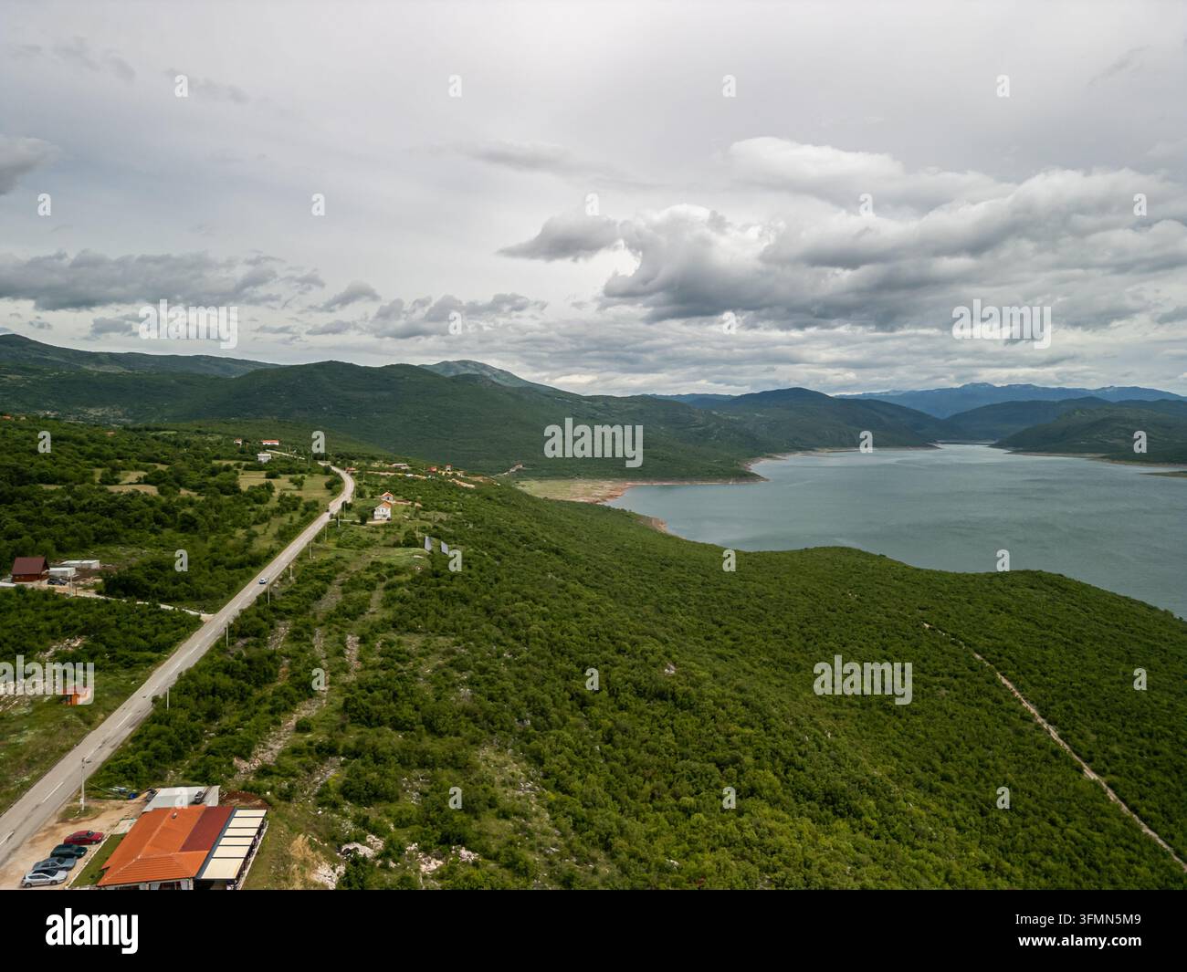 Aerial view of Bileca Lake surrounded by lush green hills, a winding ...