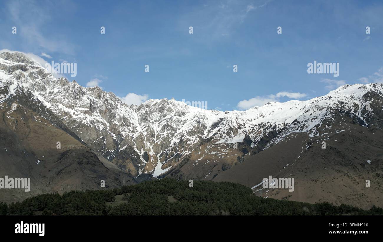 Aerial view of the snow-covered Caucasus Mountains with rocky peaks ...