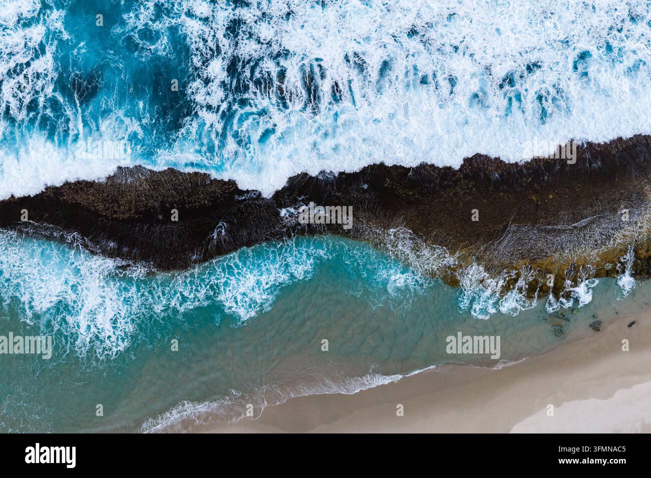 Aerial view of waves crashing against the rocky coastline and sandy ...
