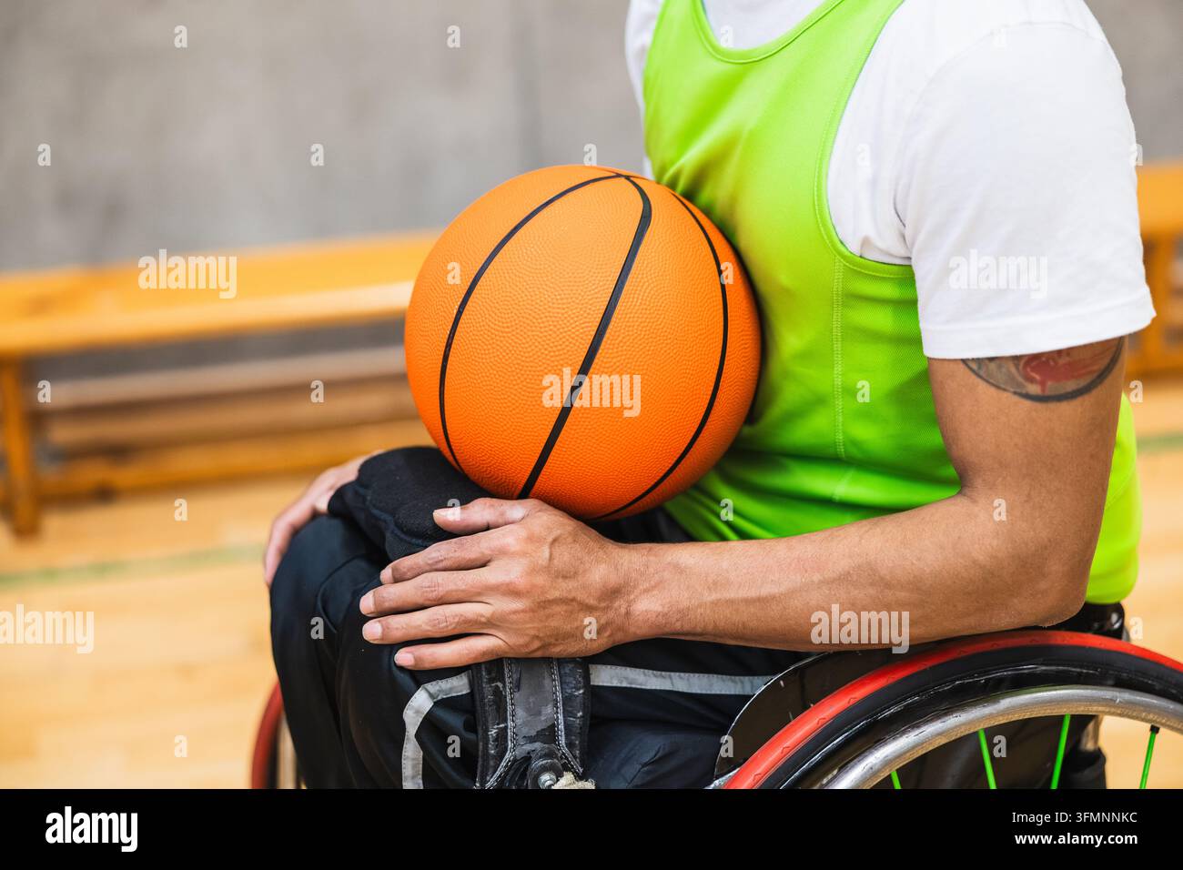 Athlete holding basketball while sitting in wheelchair on court Stock Photo